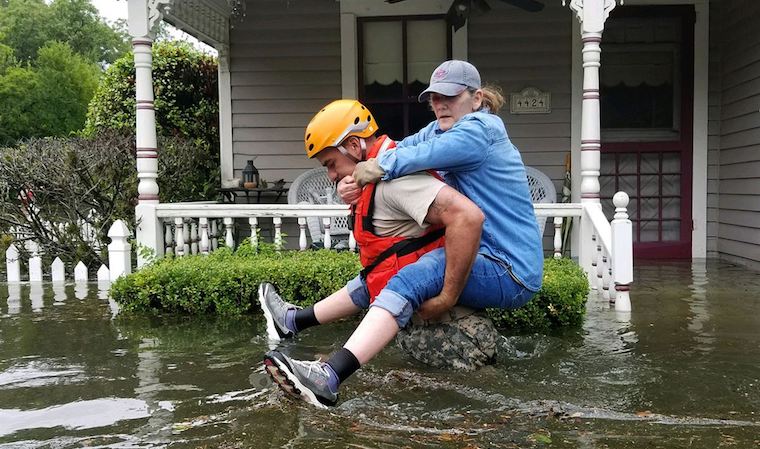 A Texas National Guardsman carries a residents from her home during flooding caused by Hurricane Harvey