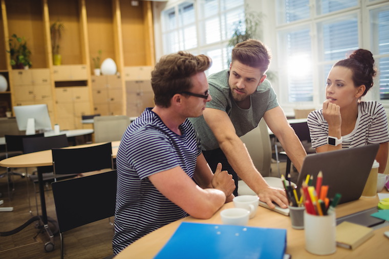 Group of business executives discussing over laptop at their desk