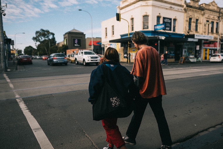 housing first, man and woman walking across Melbourne street