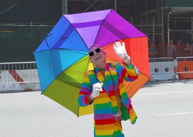LGBTIQ+ man wearing rainbow suit holding rainbow umbrella