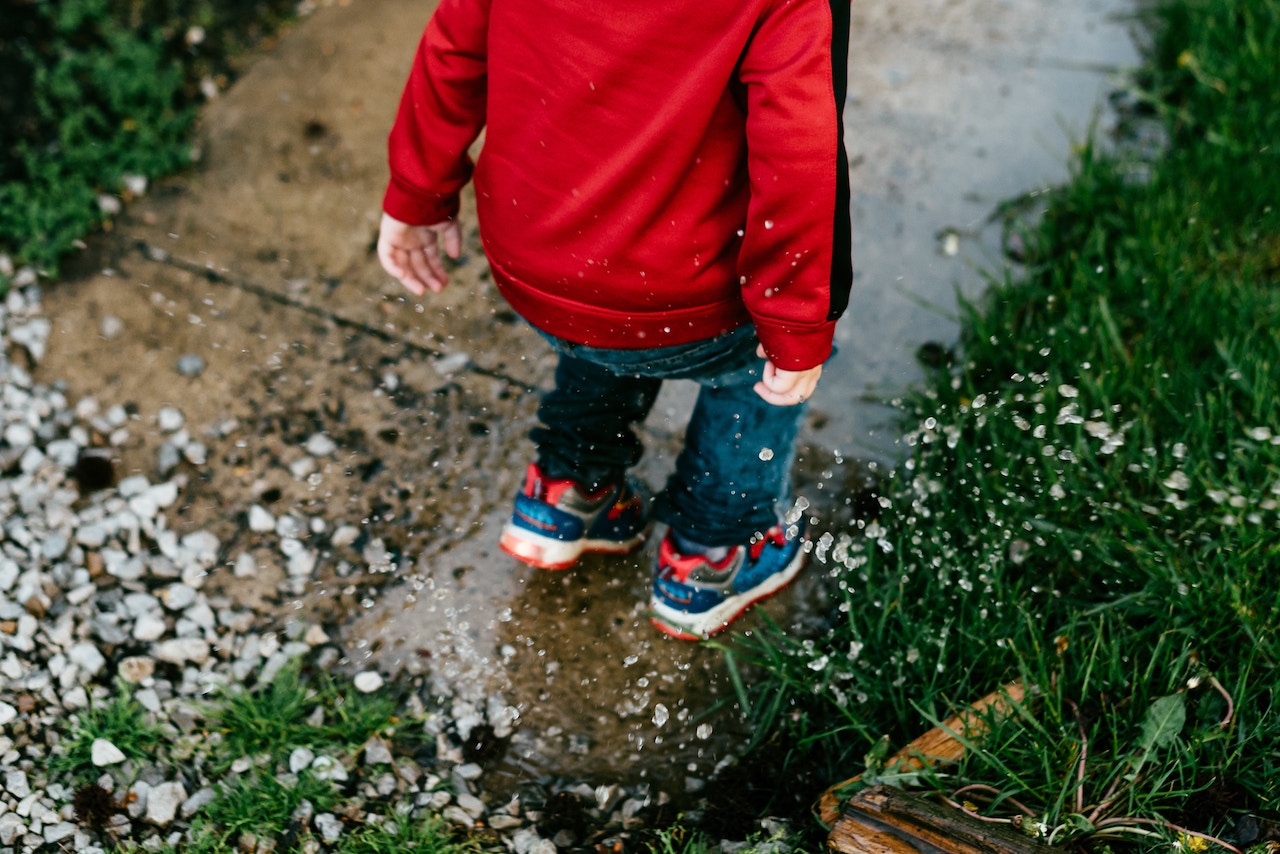 kid jumping in puddle raining