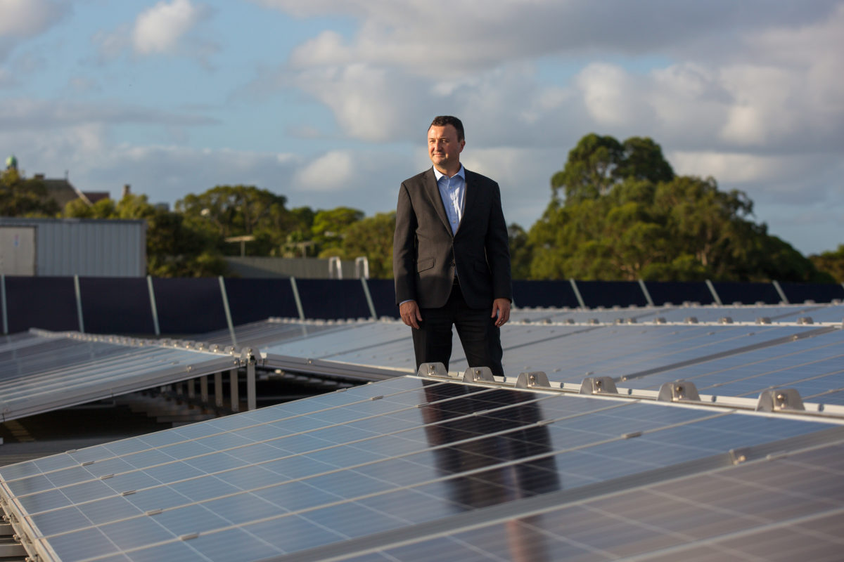 man in suit standing with solar panels