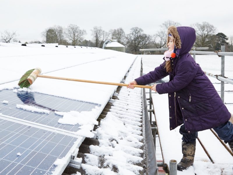 girl cleaning snow off solar panel