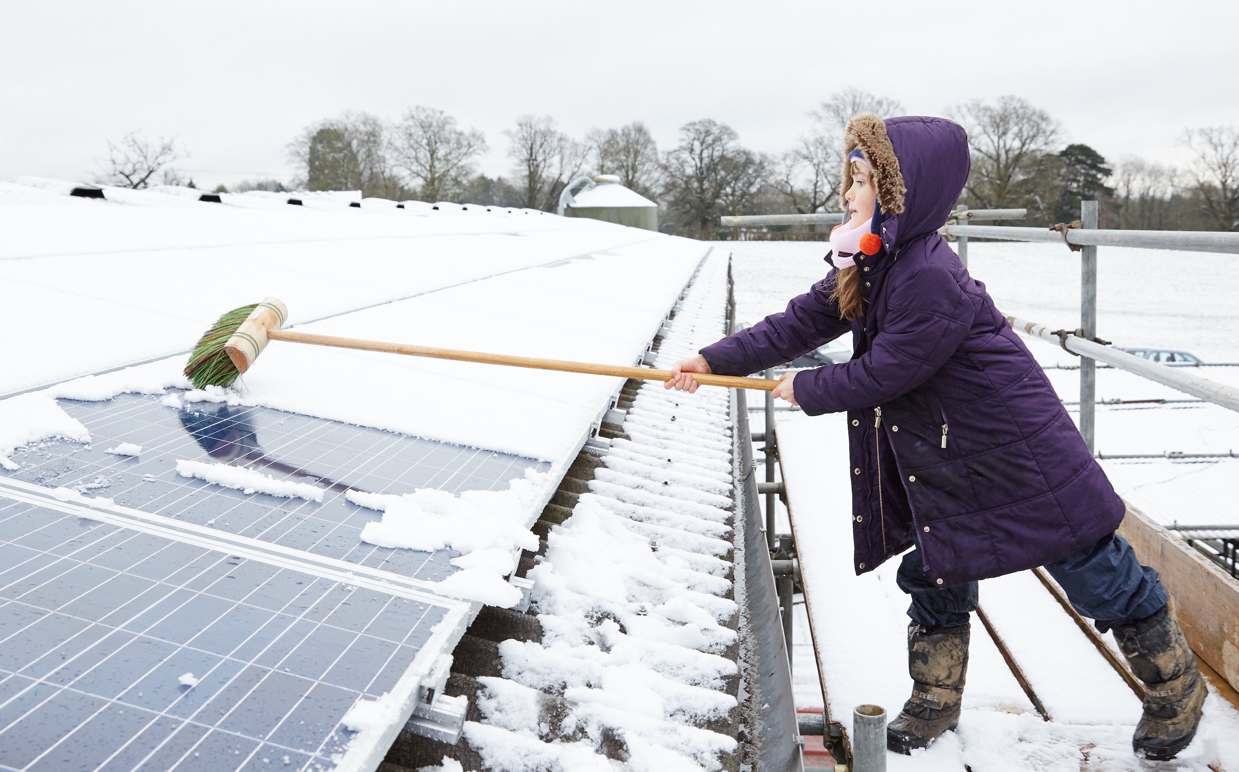 girl cleaning snow off solar panel