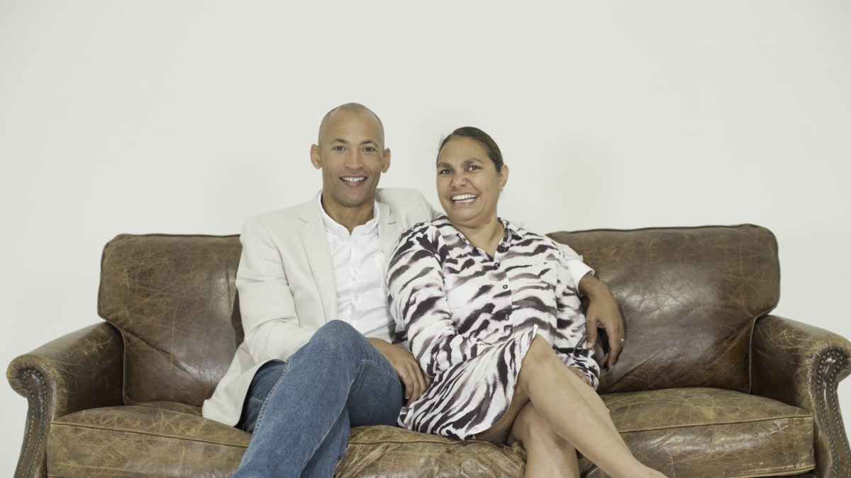 husband and wife smiling, sitting on sofa