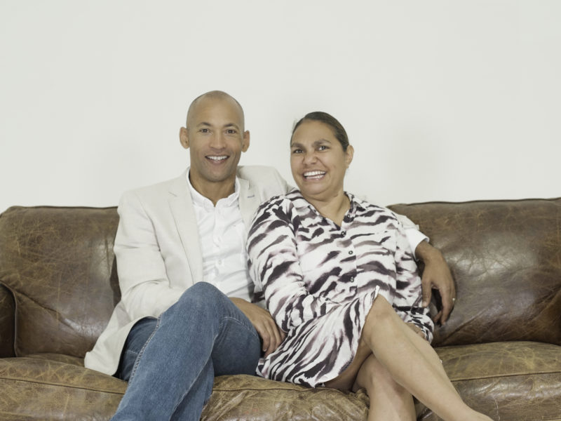 husband and wife smiling, sitting on sofa