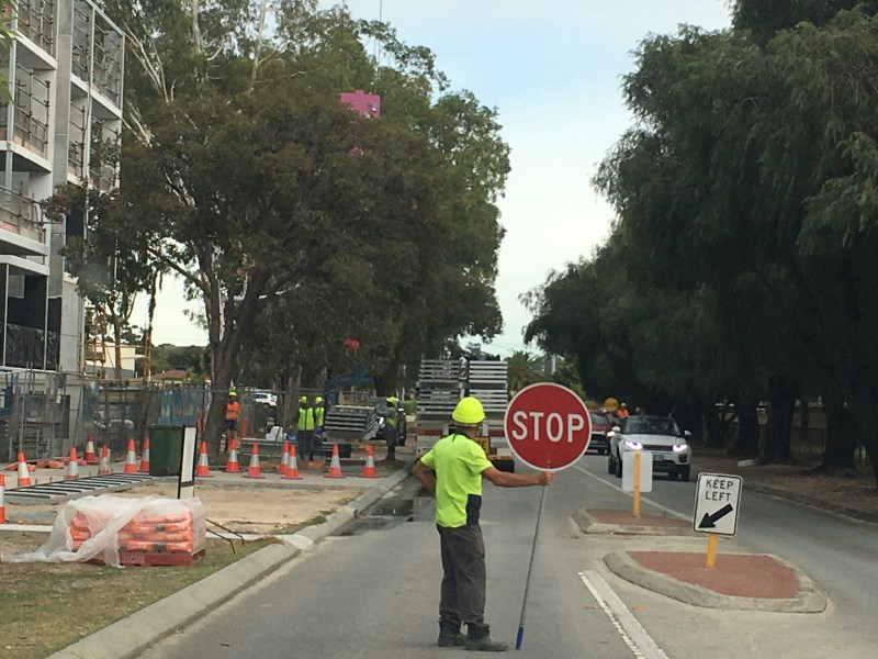 PERTH, WA - APR 23 2021:Builder holding a stop sign outside building site.Construction industry accounts for more than 10% of global GDP and employs around 7% of the global workforce over 273m people.