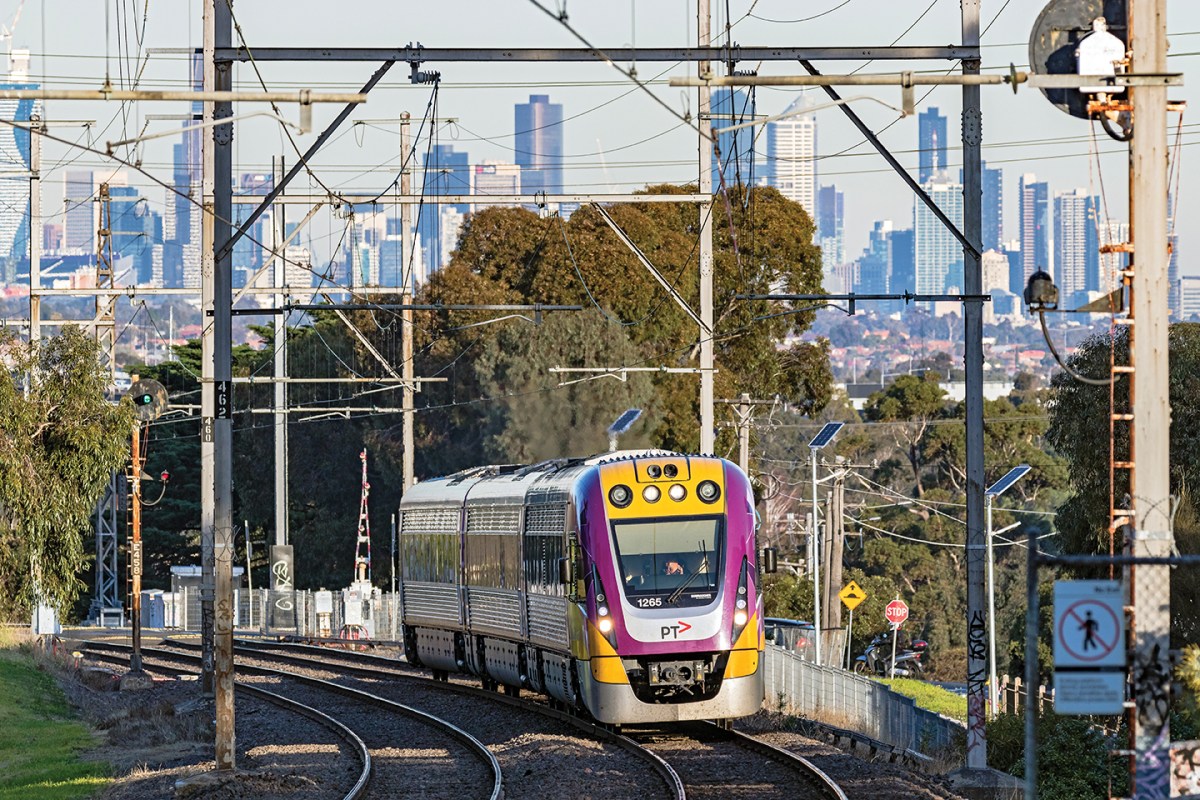 Melbourne, Australia – June 16, 2017: Modern Bombardier Velocity 3-car regional train with PTV logo and latest colours climbs uphill on a Seymour service with the downtown city centre in the background. Close-up view.