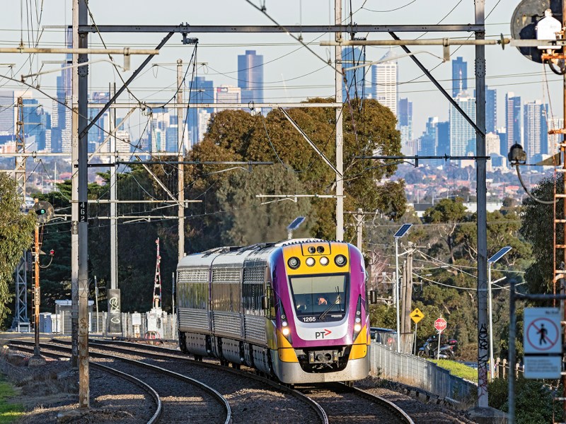 Melbourne, Australia – June 16, 2017: Modern Bombardier Velocity 3-car regional train with PTV logo and latest colours climbs uphill on a Seymour service with the downtown city centre in the background. Close-up view.