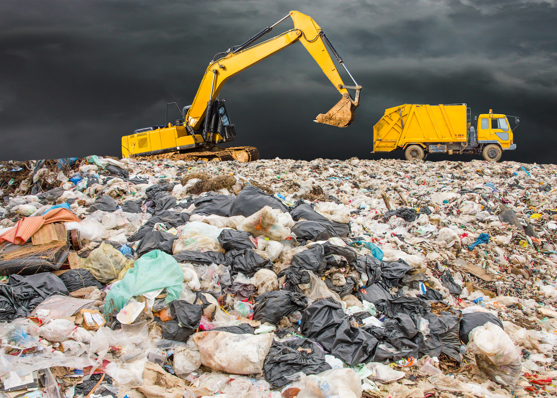 garbage dump pile in trash dump or landfill,backhoe and truck is dumping the gabage from municipal,garbage dump whit old garbage truck and dark clouds or rain clouds