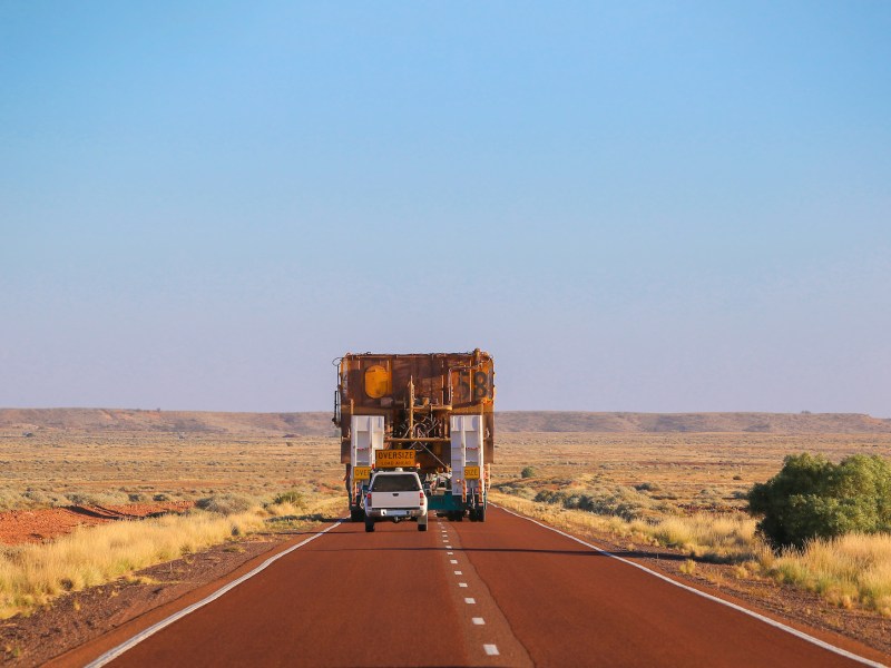 Rear view. Truck oversize rides on road. Large truck driven mining dumper. Load ahead