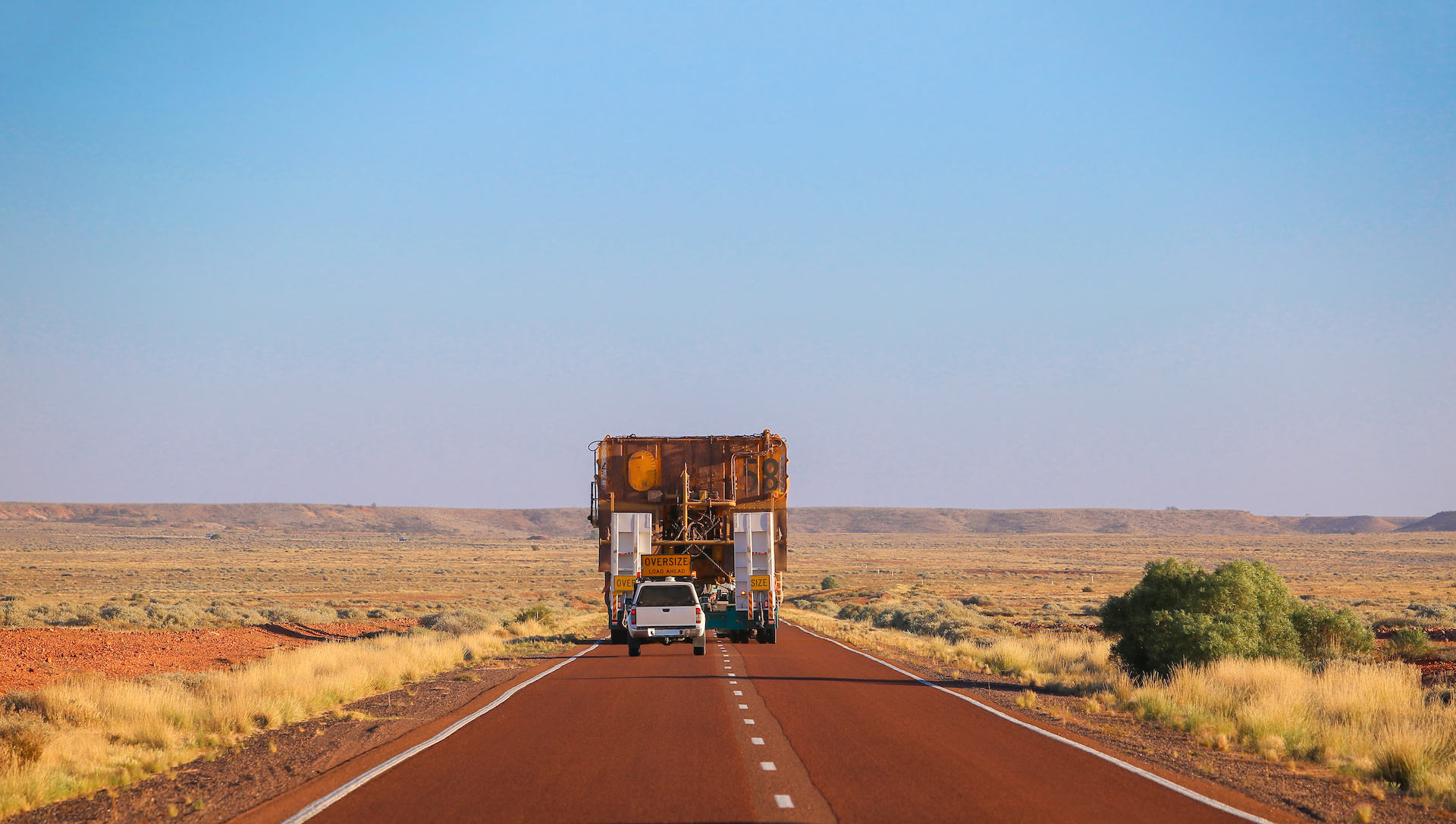 Rear view. Truck oversize rides on road. Large truck driven mining dumper. Load ahead