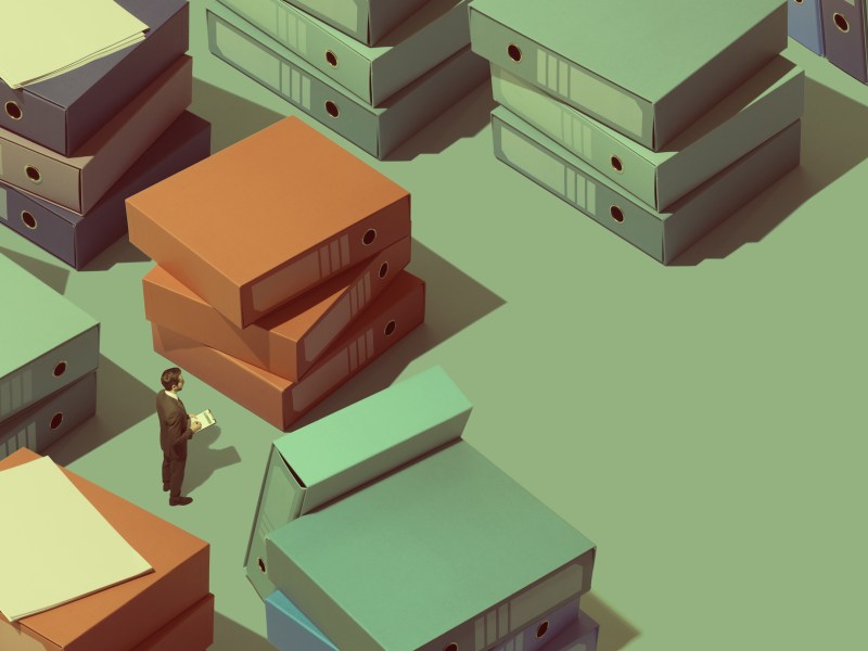 Businessman lost between piles of paperwork and folders, business management concept