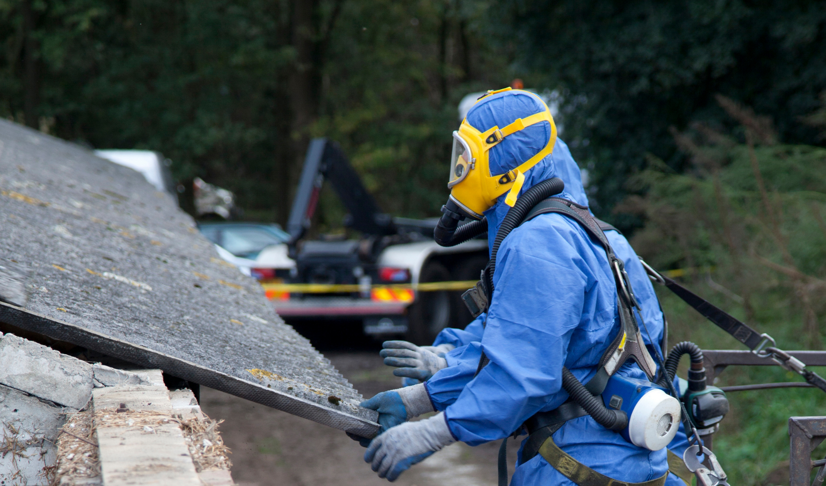 worker removing asbestos with protective PPE gear
