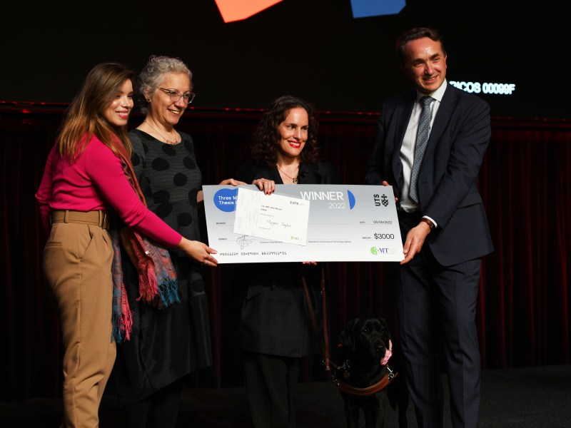 Winner Megan Taylor with the prize cheque, standing surrounded by three judges.