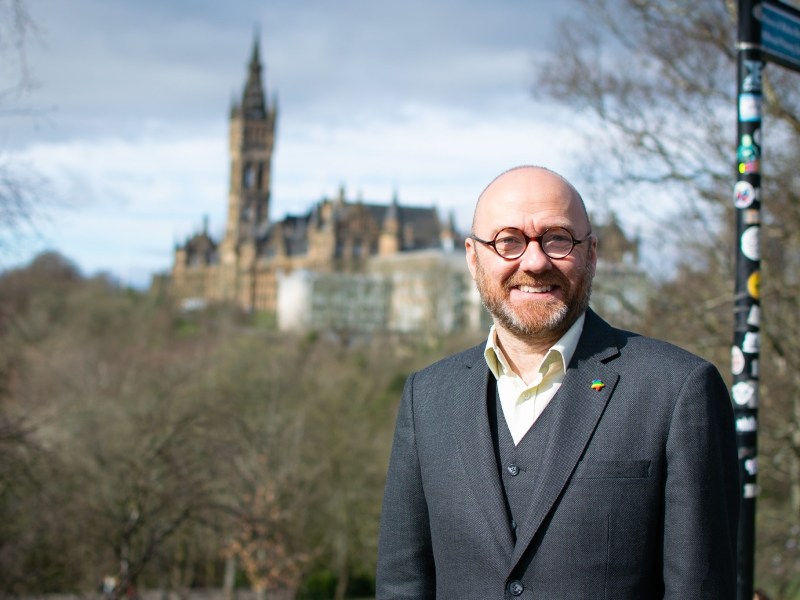 Man with glasses wearing a suit standing in front of a historical building