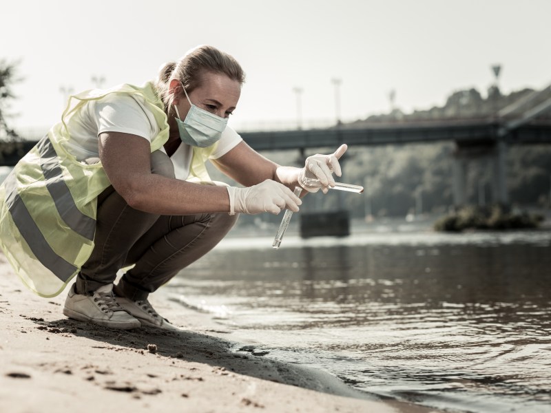 Water contamination. Professional sanitary inspector holding test tubes with water while checking water contamination level