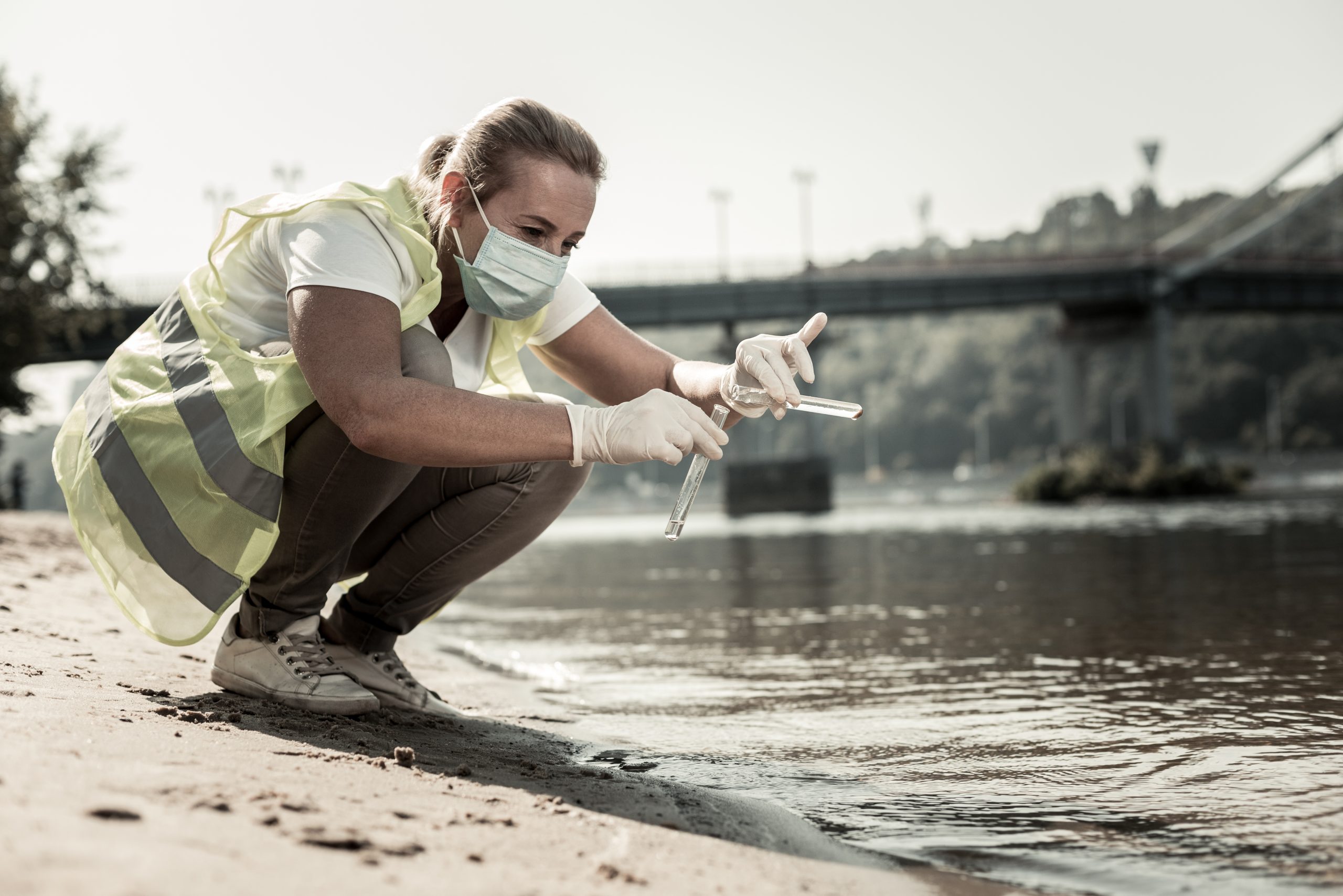 Water contamination. Professional sanitary inspector holding test tubes with water while checking water contamination level