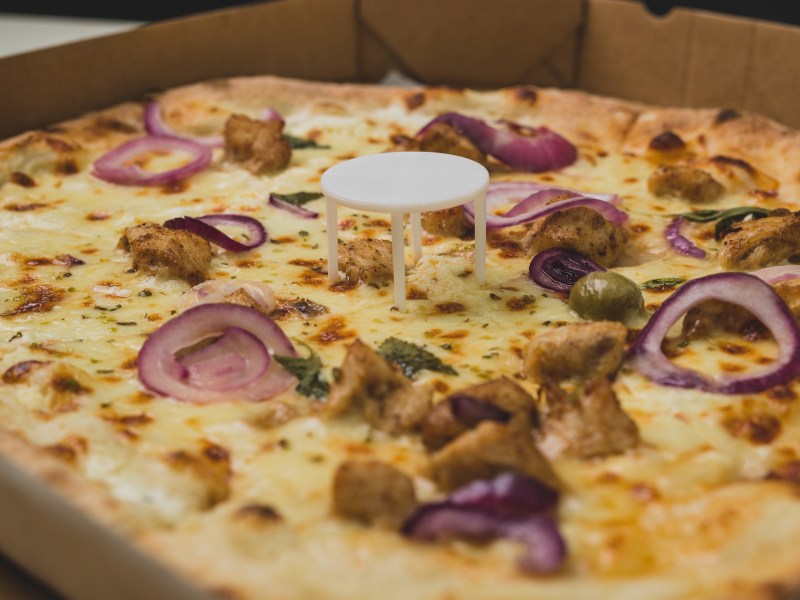 Pizza saver as pizza table, used in pizza deliveries to save the pizza being squished in a cardboard box. Tasty delicious pizza being saved by pizza saver.