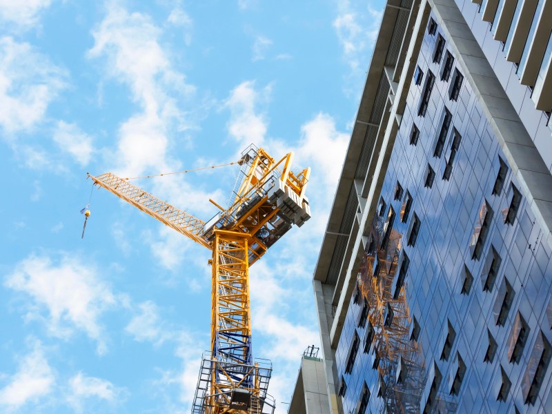 Low angle view of construction site with tower crane against blue sky, Sydney Australia, full frame horizontal composition with copy space