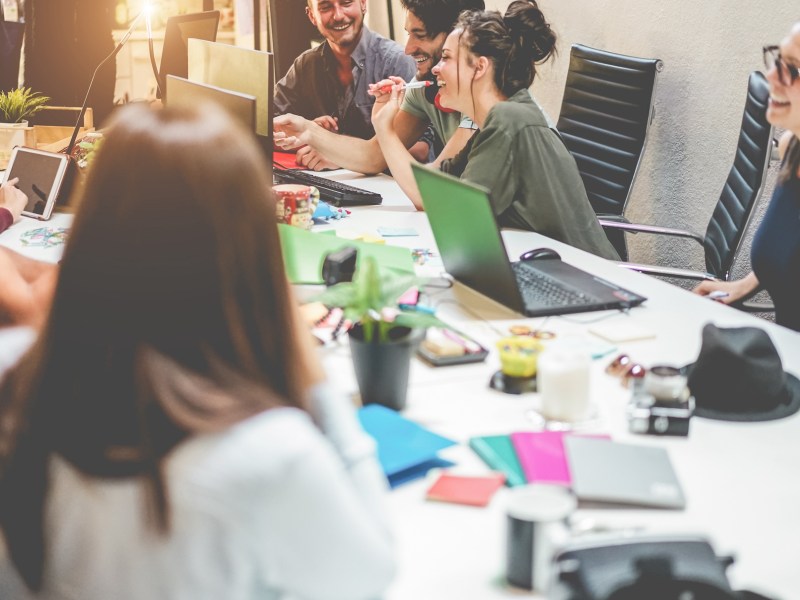 Young co-workers team talking during startup - Happy people planning a new project in creative workplace office - Focus on right top men - Technology, entrepreneur, marketing concept