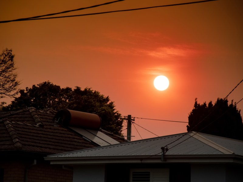 Australian bushfire: smoke from bushfires covers the sky and yellow and red sunset above the roofs looks frightening. Suburb in a smoke haze. Catastrophic fire danger, NSW, Australia
