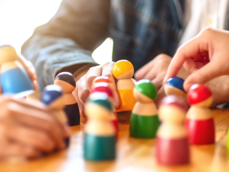 People choosing and picking up wooden figure from a group on the table