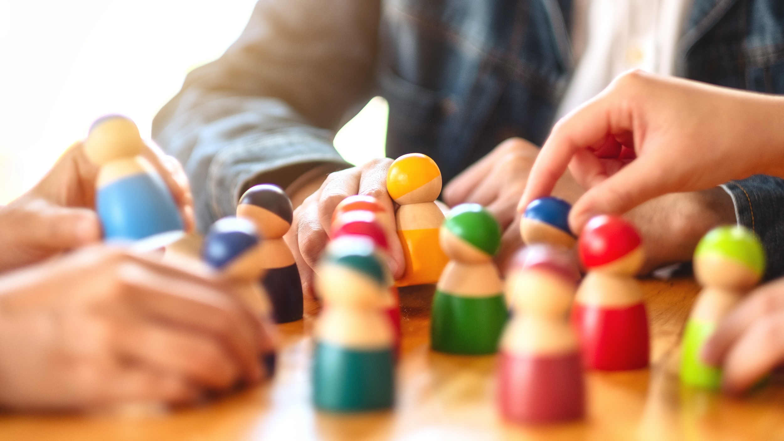 People choosing and picking up wooden figure from a group on the table