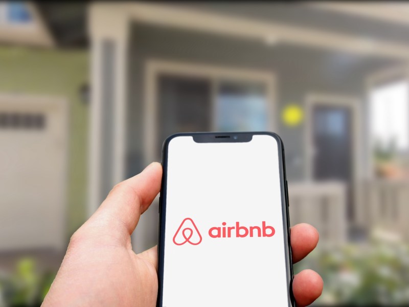 hand holding Smartphone with Airbnb Logo on it. editorial use only