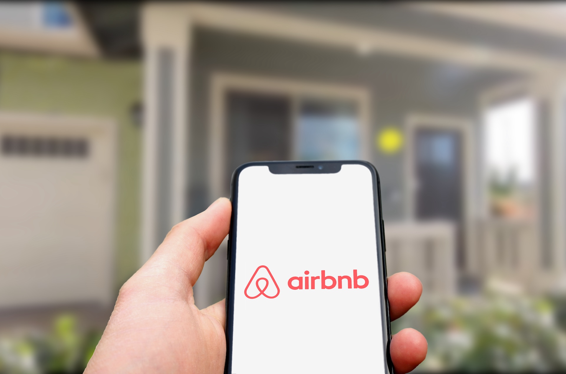 hand holding Smartphone with Airbnb Logo on it. editorial use only