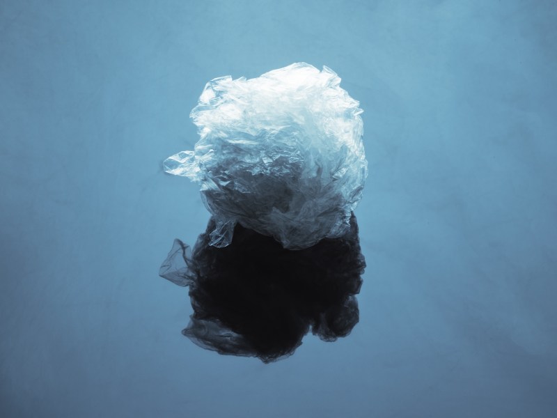 Crumpled plastic wrap on a blue surface with reflection.