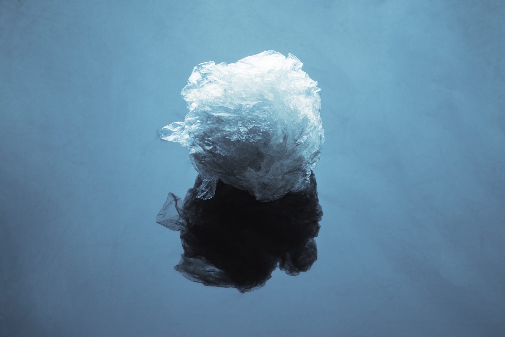 Crumpled plastic wrap on a blue surface with reflection.
